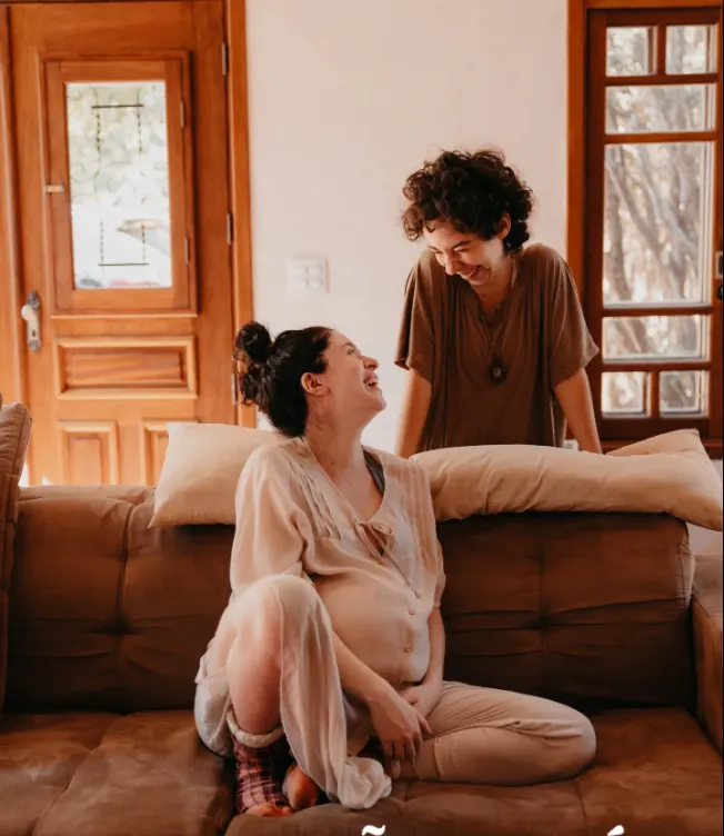 Anahí conversando com uma gestante na sala de casa